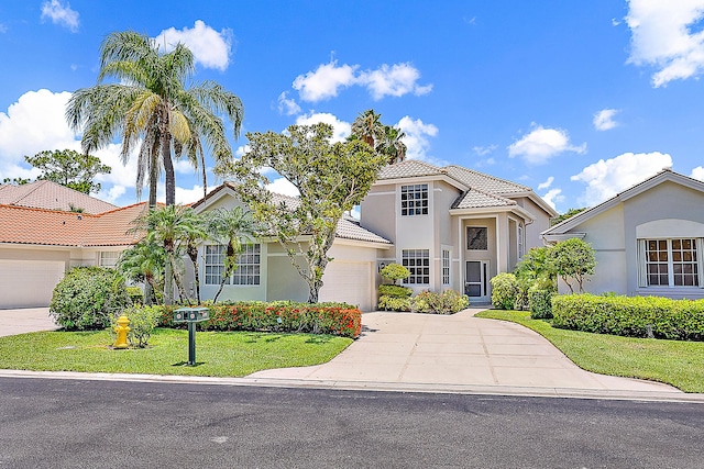 313 Eagleton Golf Dr, Palm Beach Gardens, FL 33418 - mediterranean / spanish-style house featuring an attached garage, driveway, a tiled roof, stucco siding, and a front yard