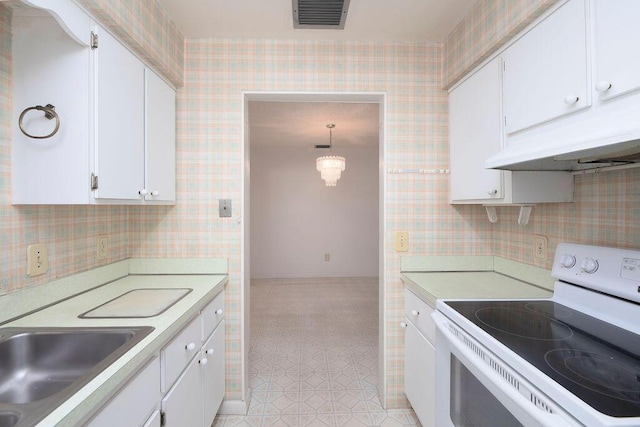 325 SE Bayview Ter, Port Saint Lucie, FL 34983 - kitchen with white range with electric stovetop, white cabinets, light countertops, under cabinet range hood, and wallpapered walls