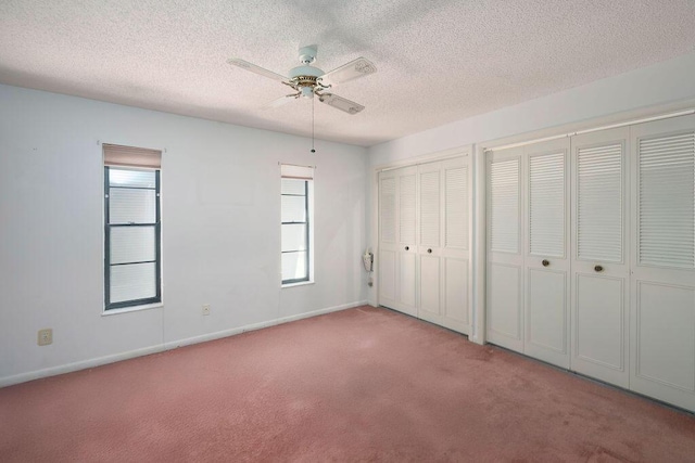 325 SE Bayview Ter, Port Saint Lucie, FL 34983 - unfurnished bedroom with carpet, two closets, a textured ceiling, multiple windows, and ceiling fan