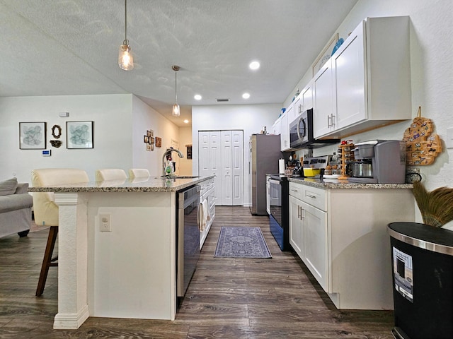 690 NE 150th Ct, Morriston, FL 32668 - kitchen with appliances with stainless steel finishes, dark wood-style floors, a breakfast bar area, light stone counters, and a kitchen island with sink