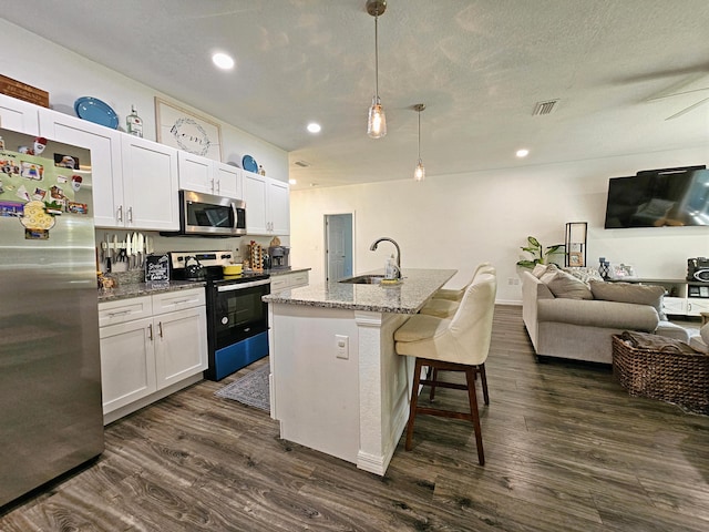 690 NE 150th Ct, Morriston, FL 32668 - kitchen featuring appliances with stainless steel finishes, open floor plan, dark wood-style floors, a breakfast bar, and recessed lighting