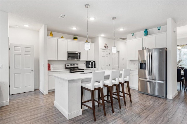 5371 NW Almond Ave, Port Saint Lucie, FL 34986 - kitchen with stainless steel appliances, light wood-style floors, light countertops, white cabinetry, and recessed lighting
