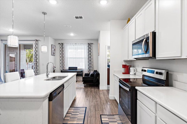 5371 NW Almond Ave, Port Saint Lucie, FL 34986 - kitchen with appliances with stainless steel finishes, light countertops, white cabinetry, light wood-style floors, and a textured ceiling