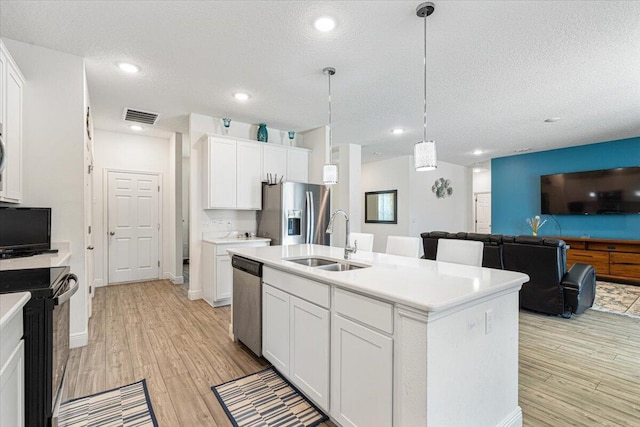 5371 NW Almond Ave, Port Saint Lucie, FL 34986 - kitchen featuring stainless steel appliances, a textured ceiling, light wood finished floors, light countertops, and white cabinets