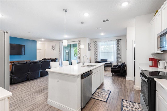 5371 NW Almond Ave, Port Saint Lucie, FL 34986 - kitchen with appliances with stainless steel finishes, open floor plan, white cabinets, light countertops, and light wood finished floors