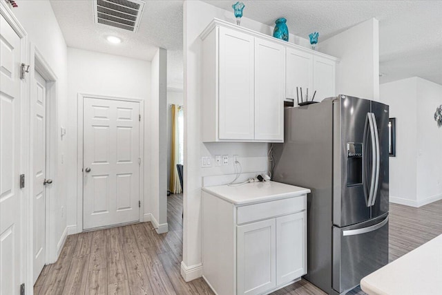 5371 NW Almond Ave, Port Saint Lucie, FL 34986 - kitchen featuring stainless steel refrigerator with ice dispenser, a textured ceiling, light wood finished floors, white cabinets, and light countertops