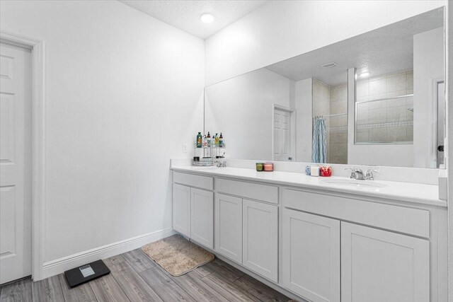5371 NW Almond Ave, Port Saint Lucie, FL 34986 - full bathroom with a textured ceiling, double vanity, tiled shower, and wood finished floors