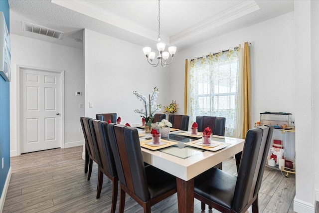 5371 NW Almond Ave, Port Saint Lucie, FL 34986 - dining space featuring ornamental molding, a raised ceiling, a chandelier, and light wood finished floors