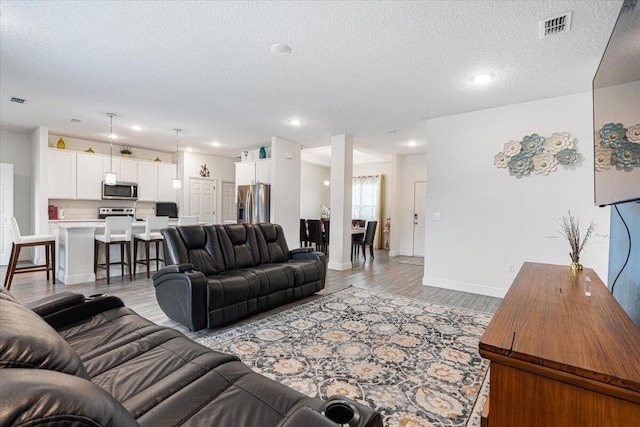 5371 NW Almond Ave, Port Saint Lucie, FL 34986 - living room with light wood-style floors, a textured ceiling, and recessed lighting