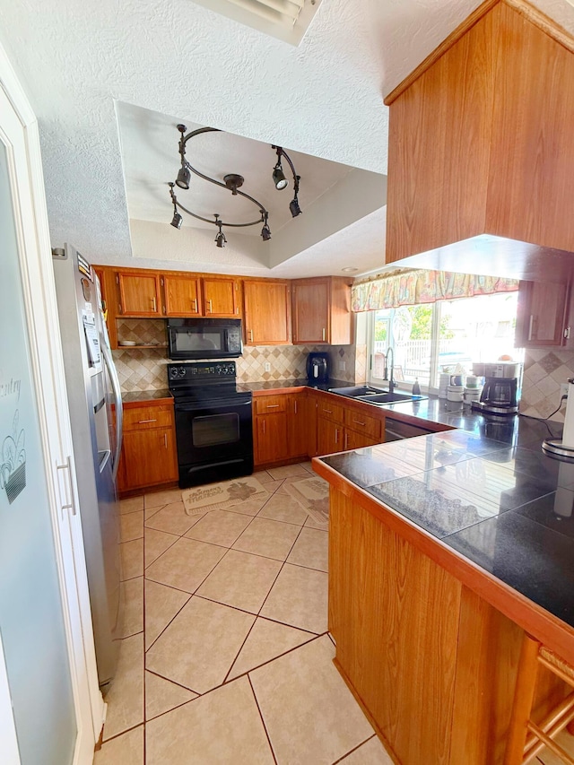637 SW Sail Ter, Port Saint Lucie, FL 34953 - kitchen featuring black appliances, brown cabinetry, backsplash, a textured ceiling, and light tile patterned flooring