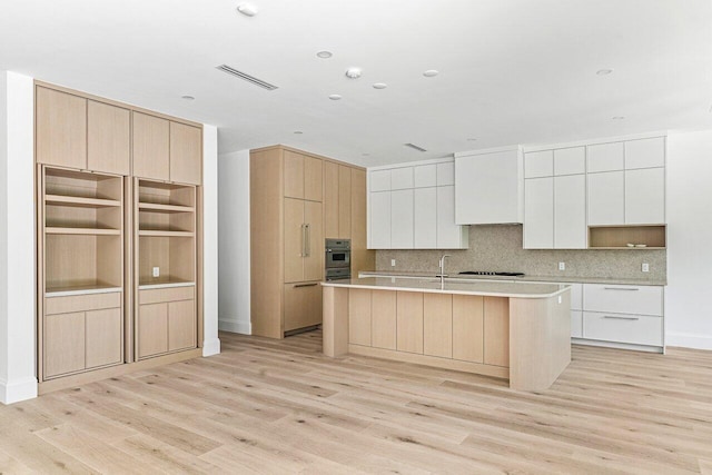 471 NW 9th St, Boca Raton, FL 33432 - kitchen with modern cabinets, light wood finished floors, an island with sink, and gas cooktop