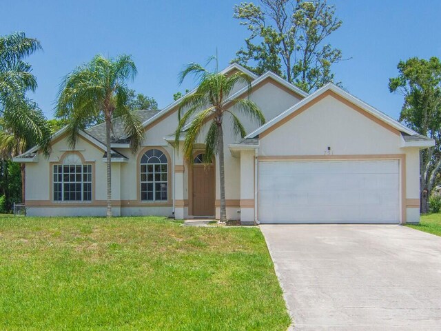 751 SE Majestic Ter, Port Saint Lucie, FL 34953 - view of front of house featuring stucco siding, a garage, driveway, and a front yard