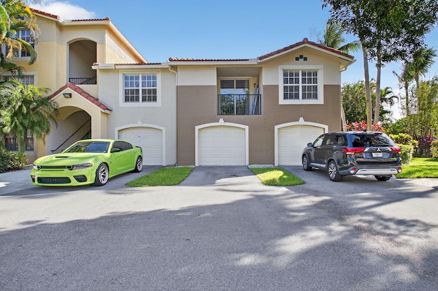 15185 Michelangelo Blvd Unit 207, Delray Beach, FL 33446 - view of front of home featuring driveway, a tiled roof, stucco siding, and a garage