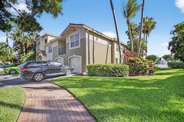 15185 Michelangelo Blvd Unit 207, Delray Beach, FL 33446 - view of side of home with stucco siding, a yard, and a garage