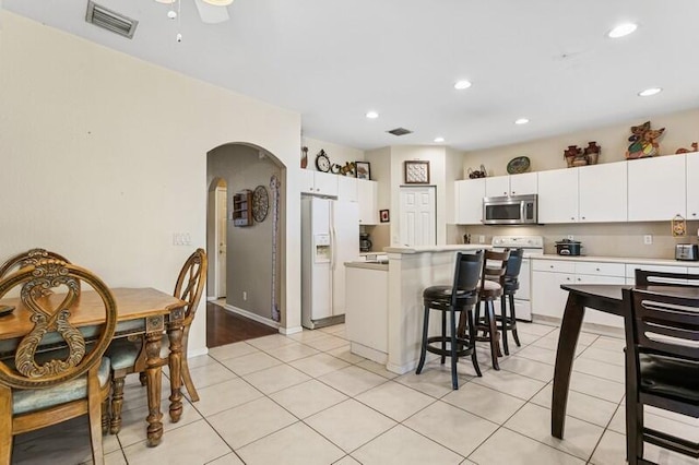 315 Spruce St, Boynton Beach, FL 33426 - kitchen featuring white appliances, arched walkways, light countertops, a kitchen bar, and recessed lighting