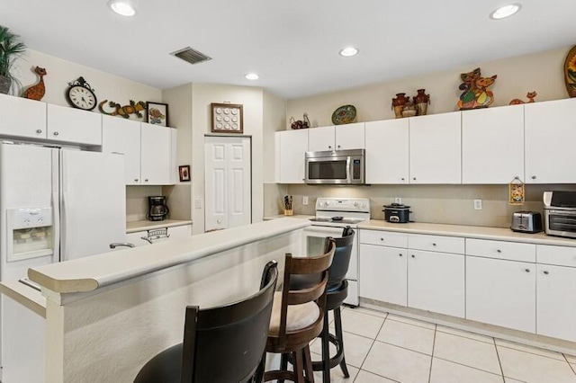 315 Spruce St, Boynton Beach, FL 33426 - kitchen featuring white appliances, a kitchen breakfast bar, light countertops, white cabinetry, and recessed lighting