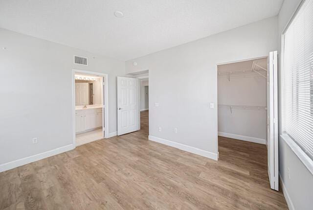 11765 W Atlantic Blvd Unit 1626, Coral Springs, FL 33071 - unfurnished bedroom featuring light wood finished floors, a spacious closet, a closet, and connected bathroom