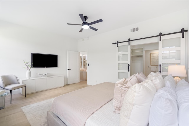 5189 Lake Catalina Dr Unit A, Boca Raton, FL 33496 - bedroom with a barn door, light wood-style floors, a walk in closet, a ceiling fan, and ensuite bath