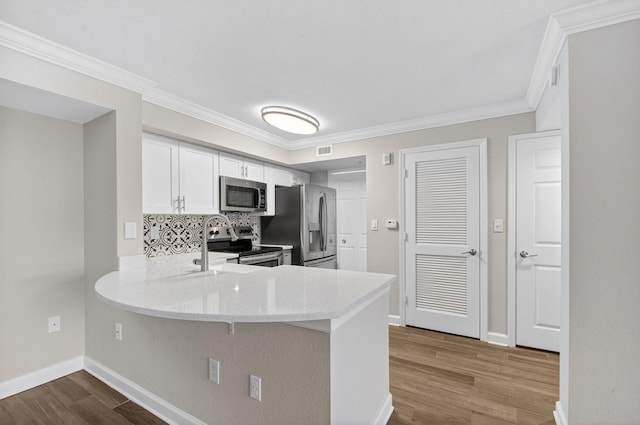 15155 Michelangelo Blvd Unit 103, Delray Beach, FL 33446 - kitchen featuring appliances with stainless steel finishes, dark wood-style floors, a peninsula, white cabinets, and decorative backsplash
