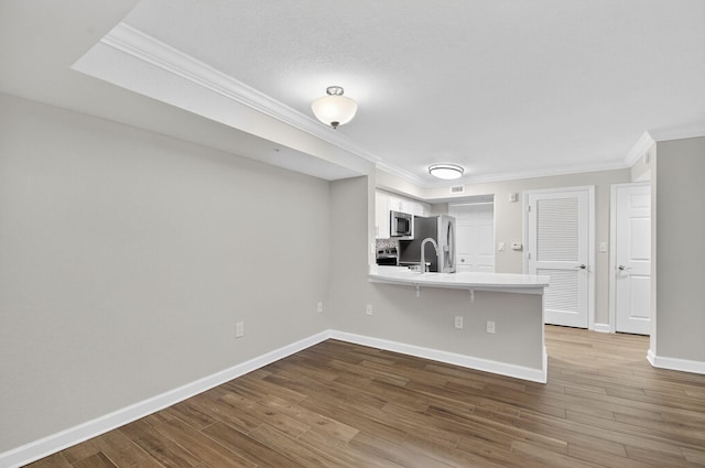 15155 Michelangelo Blvd Unit 103, Delray Beach, FL 33446 - kitchen with stainless steel appliances, a peninsula, crown molding, light countertops, and wood finished floors