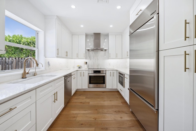 1116 SE 11th St, Fort Lauderdale, FL 33316 - kitchen featuring stainless steel appliances, wall chimney exhaust hood, white cabinetry, light stone countertops, and recessed lighting