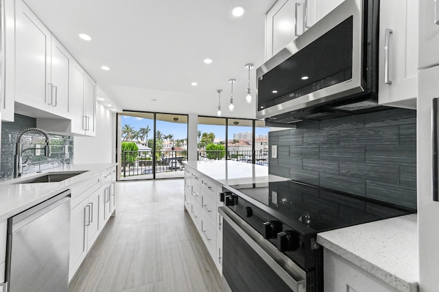 899 Jeffery St Unit 208, Boca Raton, FL 33487 - kitchen featuring stainless steel appliances, backsplash, floor to ceiling windows, white cabinets, and light stone counters