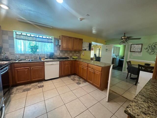 1910 SE Rainier Rd, Port Saint Lucie, FL 34952 - kitchen featuring white dishwasher, backsplash, brown cabinetry, a peninsula, and ceiling fan