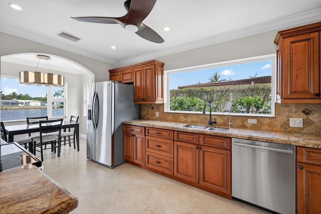 1921 W Terra Mar Dr, Lauderdale By The Sea, FL 33062 - kitchen featuring stainless steel appliances, brown cabinetry, ceiling fan, ornamental molding, and decorative backsplash