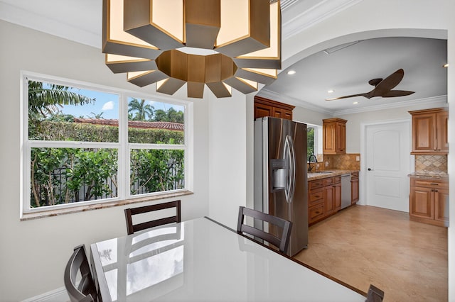 1921 W Terra Mar Dr, Lauderdale By The Sea, FL 33062 - kitchen featuring appliances with stainless steel finishes, a ceiling fan, backsplash, ornamental molding, and brown cabinetry