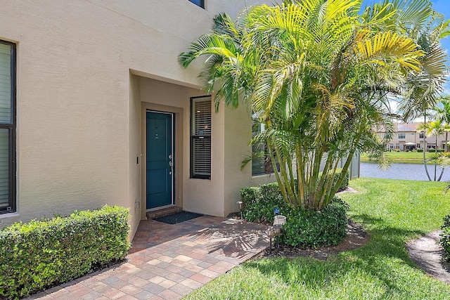 2366 Byron St, Palm Springs, FL 33406 - doorway to property featuring stucco siding, a water view, and a yard
