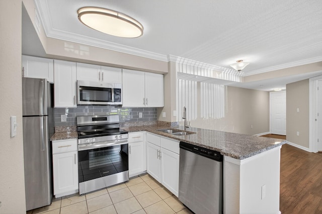 15035 Michelangelo Blvd Unit 105, Delray Beach, FL 33446 - kitchen with stainless steel appliances, a peninsula, white cabinetry, ornamental molding, and decorative backsplash