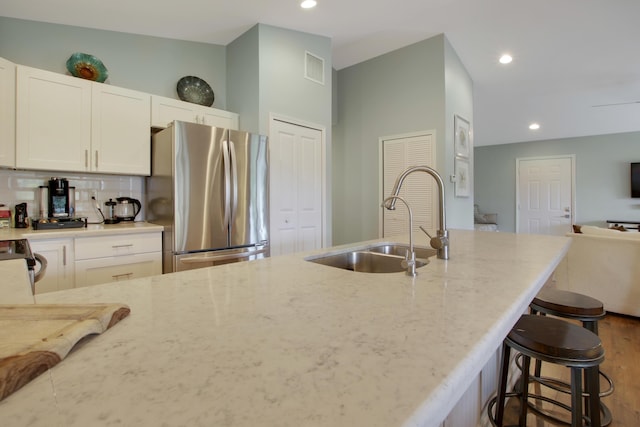 9155 SE Athena St, Hobe Sound, FL 33455 - kitchen featuring stainless steel appliances, light stone counters, a kitchen breakfast bar, recessed lighting, and decorative backsplash