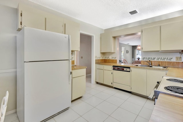 1600 SE Saint Lucie Blvd SE Unit 211, Stuart, FL 34996 - kitchen with white appliances, cream cabinetry, light countertops, a textured ceiling, and light tile patterned floors