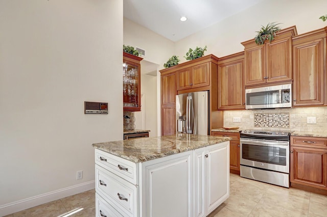 13308 Verdun Dr, Palm Beach Gardens, FL 33410 - kitchen featuring stainless steel appliances, backsplash, light tile patterned flooring, light stone counters, and a kitchen island