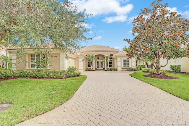 8732 Bally Bunion Rd, Port Saint Lucie, FL 34986 - mediterranean / spanish house featuring a garage, decorative driveway, stucco siding, and a front lawn