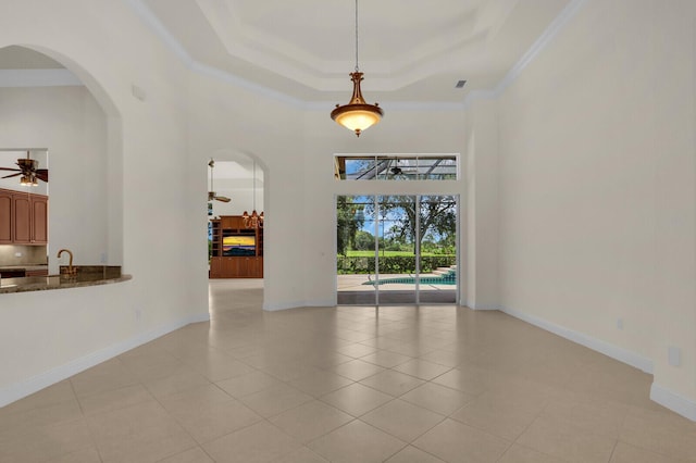 8732 Bally Bunion Rd, Port Saint Lucie, FL 34986 - empty room with a high ceiling, ornamental molding, a raised ceiling, arched walkways, and a ceiling fan