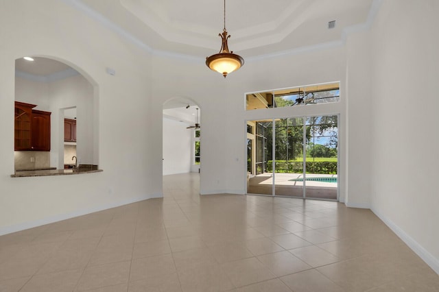 8732 Bally Bunion Rd, Port Saint Lucie, FL 34986 - empty room with arched walkways, a high ceiling, light tile patterned floors, a tray ceiling, and ceiling fan