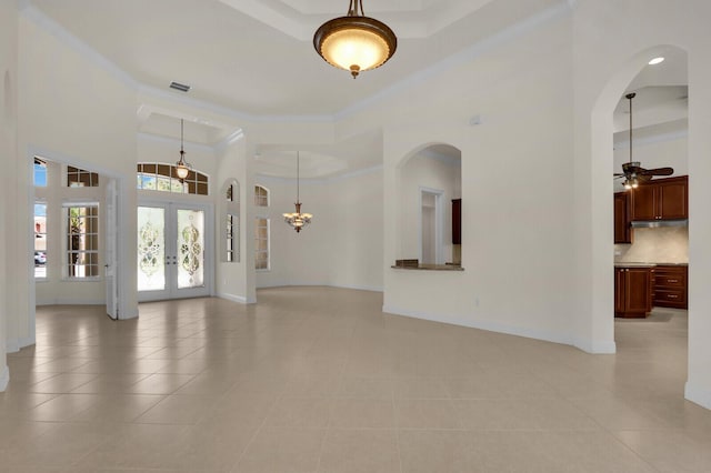 8732 Bally Bunion Rd, Port Saint Lucie, FL 34986 - unfurnished living room featuring a towering ceiling, light tile patterned floors, arched walkways, a raised ceiling, and french doors