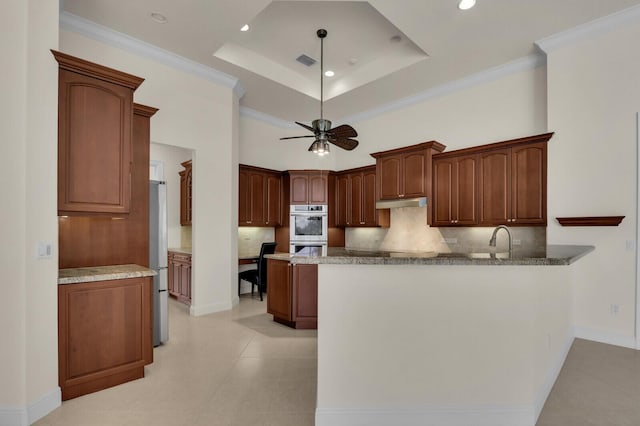 8732 Bally Bunion Rd, Port Saint Lucie, FL 34986 - kitchen featuring appliances with stainless steel finishes, tasteful backsplash, a peninsula, ceiling fan, and a tray ceiling