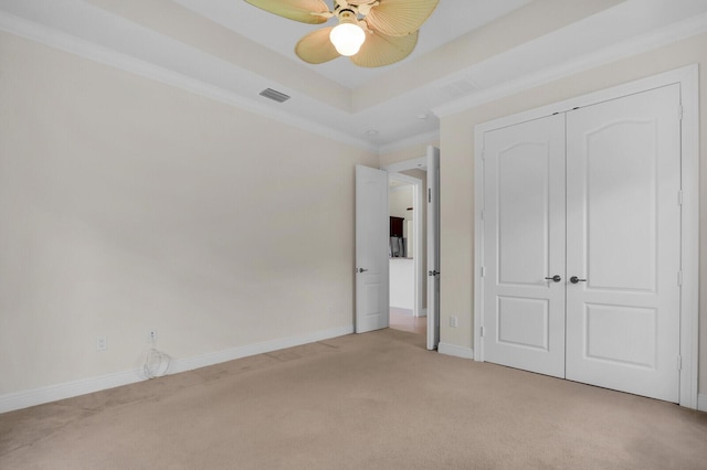 8732 Bally Bunion Rd, Port Saint Lucie, FL 34986 - unfurnished bedroom with light colored carpet, crown molding, a closet, a ceiling fan, and a tray ceiling