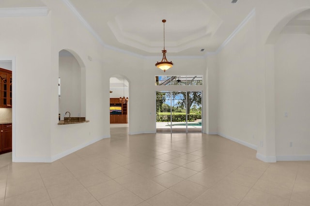 8732 Bally Bunion Rd, Port Saint Lucie, FL 34986 - empty room featuring arched walkways, crown molding, a towering ceiling, light tile patterned floors, and a tray ceiling