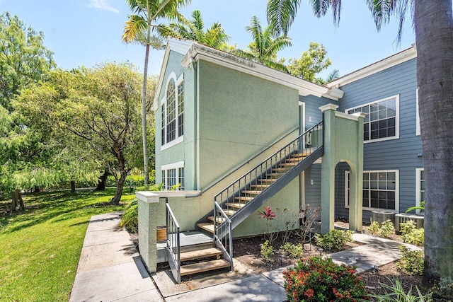 1000 Crystal Way Unit J, Delray Beach, FL 33444 - view of property exterior featuring stairs, a lawn, and stucco siding