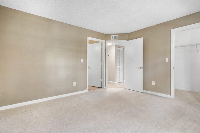 1000 Crystal Way Unit J, Delray Beach, FL 33444 - unfurnished bedroom featuring light carpet, a walk in closet, a closet, and a textured ceiling