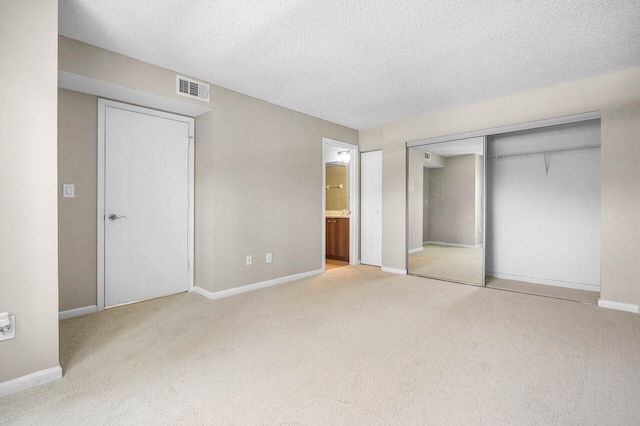 1000 Crystal Way Unit J, Delray Beach, FL 33444 - unfurnished bedroom featuring carpet flooring, a closet, a textured ceiling, and connected bathroom