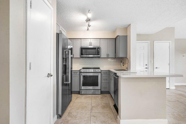1000 Crystal Way Unit J, Delray Beach, FL 33444 - kitchen with premium appliances, gray cabinetry, light tile patterned floors, tasteful backsplash, and a peninsula