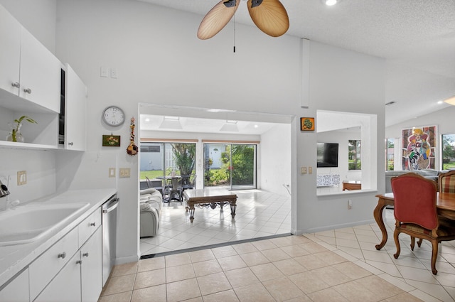 3010 NW 12th St Unit D, Delray Beach, FL 33445 - kitchen featuring light tile patterned floors, high vaulted ceiling, light countertops, white cabinets, and dishwasher