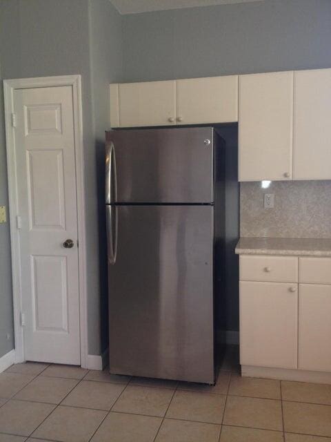 3306 Shoma Dr Unit 305, Royal Palm Beach, FL 33414 - kitchen with freestanding refrigerator, light countertops, white cabinets, light tile patterned floors, and backsplash