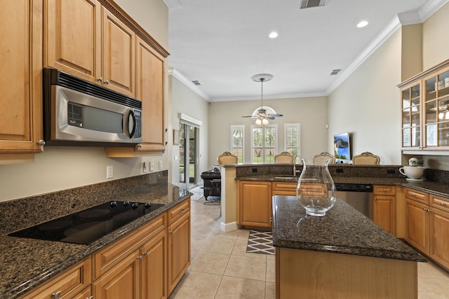 801 SW Classico Ct, Port Saint Lucie, FL 34986 - kitchen featuring appliances with stainless steel finishes, crown molding, light tile patterned floors, dark stone counters, and a kitchen island