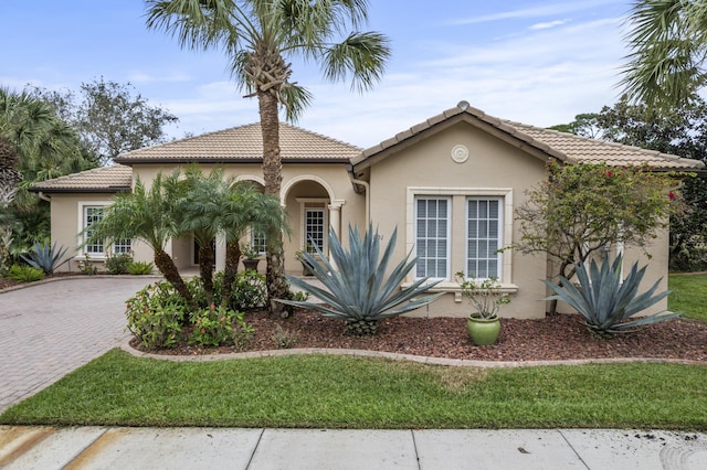 801 SW Classico Ct, Port Saint Lucie, FL 34986 - mediterranean / spanish house featuring stucco siding, decorative driveway, a tiled roof, and a front lawn