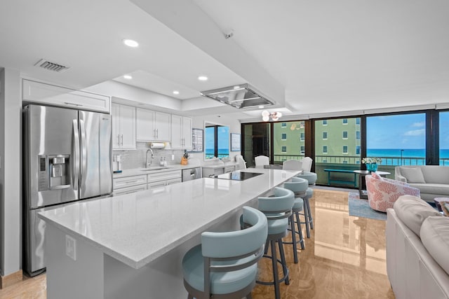 5280 N Ocean Dr Unit 3B, Singer Island, FL 33404 - kitchen with appliances with stainless steel finishes, white cabinets, open floor plan, decorative backsplash, and light stone countertops